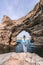 Sea woman rocks grotto. A woman in a blue jacket stands on a rock above a cliff above the sea and looks at the raging