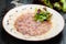 Seabass carpaccio served with arugula leaves, parmesan cheese and lettuce salad on white plate