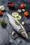 Seabass fish with herbs and lemon, raw sea bass. Black background. Top view