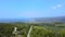 Seacoast covered by pine trees and roads and open sea behind. Aerial drone view