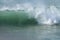 Seafoam green wave with off shore wind spray breaking in the Pacific Ocean