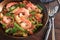 Seafood dish with prawns, rice, chicken meat and vegetables in a paella pan on a dark rustic wooden table, selected focus