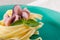 Seafood Fettuccine pasta with octopus, garnished with basil on a clay plate and fabric background