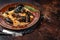 Seafood Mafaldine pasta with mussels and tomato sauce in a rustic plate. Dark background. Top view. Copy space