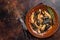 Seafood Mafaldine pasta with mussels and tomato sauce in a rustic plate. Dark background. Top view. Copy space
