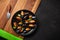 Seafood mussels and basil leaves in a black plate with lemon, knife on wooden board and stone table