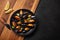 Seafood mussels and basil leaves in a black plate with lemon, knife on wooden board and stone table