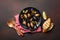 Seafood mussels and basil leaves in a black plate with towel, bread slices, wooden spoon and fork on rusty background