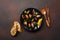 Seafood mussels and basil leaves in a black plate with towel, bread slices, wooden spoon and fork on rusty background