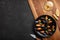 Seafood mussels and basil leaves in a black plate with wineglass, lemon, knife on wooden board and stone table