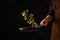 Seafood - octopus with vegetables and herbs in a pan in a frozen flight on a black background. Professional chef prepares seafood