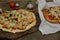 Seafood pizzas with mussels, mozzarella cheese on a wooden board and pizza on a paper on a wooden rustic table. Mediterranean food