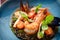 Seafood risotto black on plate on a wooden background, macro