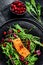 Seafood salad with salmon, arugula, lettuce and cranberries. Black background. Top view