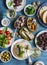 Seafood snacks table - canned sardines, mussels, octopus, grape, olives, tomato and two glasses white wine on wooden table, top vi