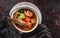 Seafood soup with langoustine, mussels, squid, fillet salmon, shrimp and celery in bowl over dark background. Healthy food, diet