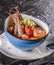 Seafood soup with langoustine, mussels, squid, fillet salmon, shrimp and celery in bowl over dark background. Healthy food, diet