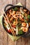 Seafood stir-fried with fresh vegetables close-up in a pan. Vertical top view