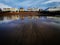 Seafront buildings reflected in wet sand.