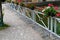 Seafront with metal railings and plastic boxes attached to the handrail. filled with dry flower decoration. benches and concrete s