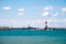 Seagull flying above breakwater, moored ship and lighthouse