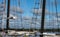 Seagull flying past rigging and ropes of sailing vessel on stomy day with shore and cloudy sky in background