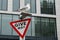 Seagull on a Give Way traffic sign in from of a modern office building in city. Constrast between technology and animal nature