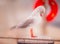 A seagull with red legs and a red beak bends his head to try and shelter from the rain. He is standing on a wooden post