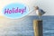 The seagull shouts `holiday` on a wooden column on the seashore