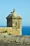 A seagull sits on a castle tower of castillo de Santa BÃ¡rbara in Alicante overlooking the Mediterranean Sea under clear blue sky