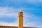 Seagull sits on a chimney on a roof against a blue sky with white clouds