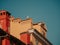 A seagull sits on the roof of an old house in the city center. Blue skies and colorful houses. Tiled roofs and ventilation pipes.