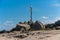 Seagull sitting on an old wooden cross on rocky lakes shore