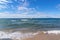 A seagull soars in the blue sky over the turquoise waters of Lake Baikal