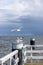 Seagull starting to fly and another standing on a large metal pole of a walkway at the pier