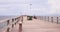 Seagulls over the wooden pier with fishermen spending the summer evening immersed in their hobby