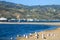 Seagulls standing on the banks of the beach surrounded by mountain ranges with homes and lush green trees