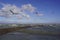 Seagulls on the waterfront fly in the sky among the clouds and the water ripples in the strong wind.