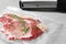 Sealer for vacuum packing with plastic bag of meat on light grey table, closeup