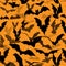 Seamless Halloween vector pattern with various flying bat silhouettes on orange background. Texture with flittermouses