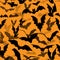 Seamless Halloween vector pattern with various flying bat silhouettes on orange background. Texture with flittermouses for