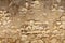 Seamless horizontal texture of an old wall made of rubble stone, brown sandstone, with the remains of cracked old plaster, a blank