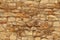 Seamless horizontal texture of an old wall made of rubble stone, brown sandstone, with the remains of cracked old plaster, a blank