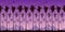 Seamless landscape pattern with silhouettes of palm trees on a background of brightly purple sunset sky and mountains.