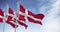 Seamless loop in slow motion of three Denmark flags waving on a clear day