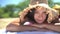 SEAMLESS LOOP VIDEO: Asian woman lying down tanning wearing straw hat on beach