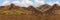 Seamless panorama of mountains under blue sky with thick clouds and green meadow valley. View from a cliff on highland terrain.