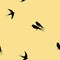 Seamless pattern with black swallow birds on a yellow background