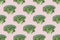 Seamless regular creative pattern of broccoli slices on a pink background.