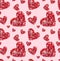 Seamless texture of red hearts from different buttons on a pink background.